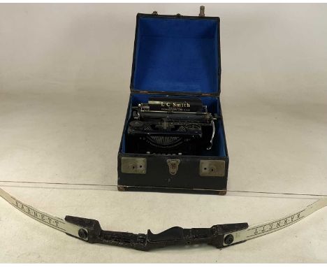L C SMITH; a black typewriter, cased, together with a Barnett bow (2)