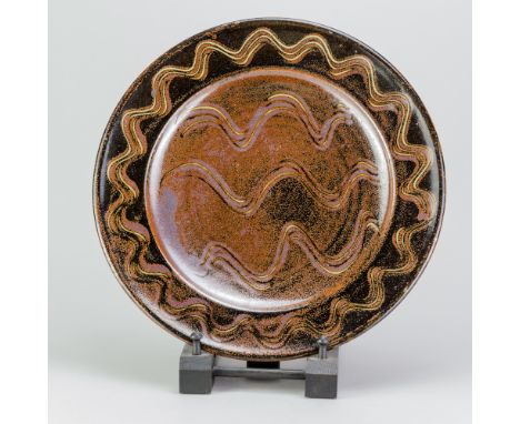 RAY FINCH (1914-2012) for Winchcombe Pottery; a stoneware charger covered in tenmoku and kaki glaze with meander decoration, 