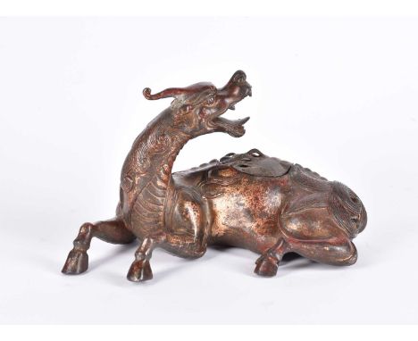 A Chinese bronze censer, modelled as a Pixiu in recumbent pose, its snarling head looking over its shoulder, a pierced lid in