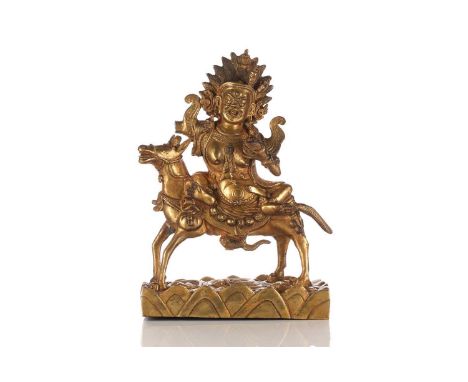 A Sino-Tibetan gilt-bronze figure of Palden Lhamo riding sideways on a mule holding a kapala in her left hand above a base of