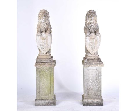 A pair of cast stone figures of standing heraldic lions each holding a shield with "lion rampant" armorial bearings on square