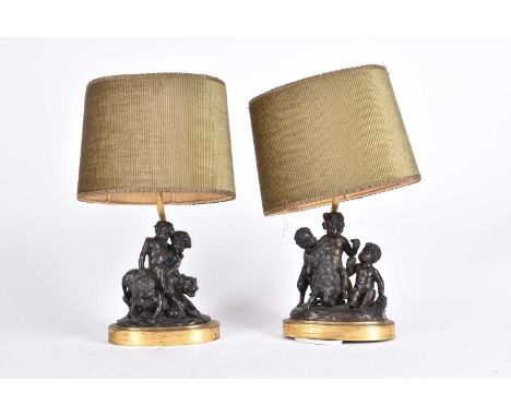 19th century French school, a pair of Bacchanalian bronze table lamps, modeled seated upon a goat and a lion with attendants,