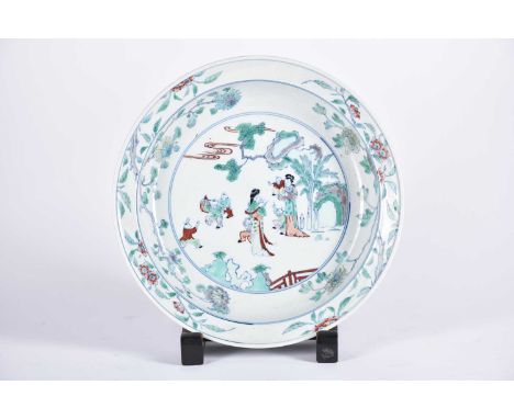 A Chinese doucai basin, painted with two standing females with six boys at play, within a landscape of rockwork, banana leave