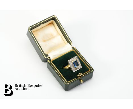 An 18ct yellow gold sapphire and diamond ring. The ring set with an emerald cut petrol blue sapphire 7.8 x 5.6mm, surrounded 