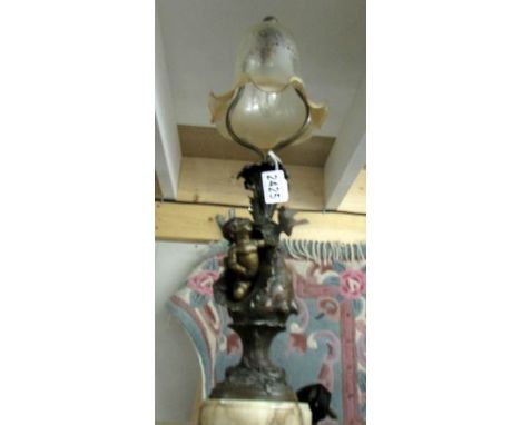 A metal table lamp surmounted cherub and bird with glass shade.