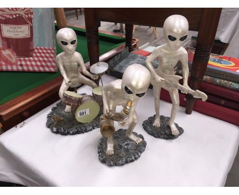 3 figures of aliens playing musical instruments