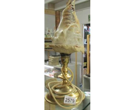 A brass table lamp with carved cameo shell shade.