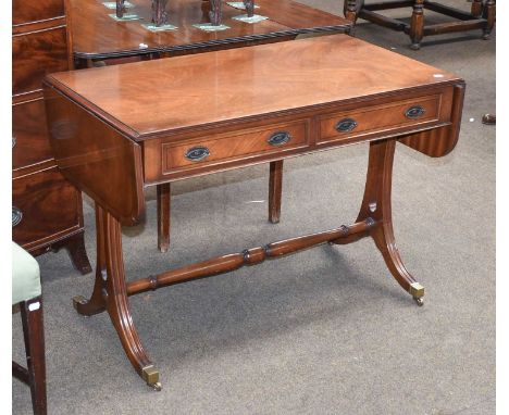 A Reproduction Mahogany Two Drawer Sofa Table, banded in yew wood, on reeded outswept supports, caped with brass castors and 