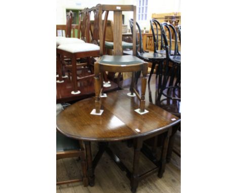 An oak oval gate leg table and three oak and leatherette chairs