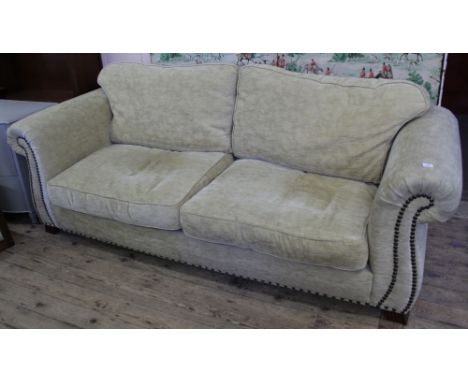 A large beige upholstered sofa with studded detail