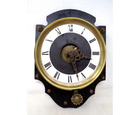 A continental brass cased wall clock with sun pendulum, mounted on a board.