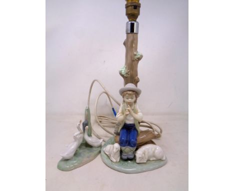 A Nao figural table lamp, seated boy, together with a further Nao figure group of geese.