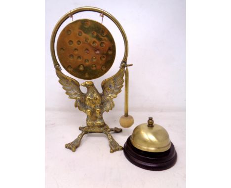 A brass dinner gong with beater on eagle stand together with a brass desk bell.