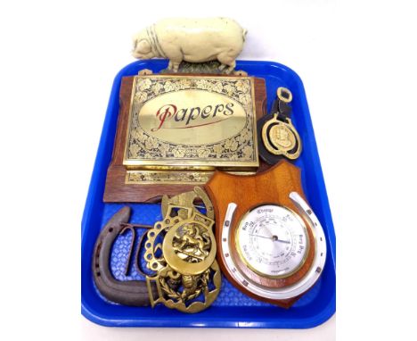 A tray containing a pig cast iron doorstop, a brass paper rack mounted on a board, horse brasses, a horse shoe barometer etc.