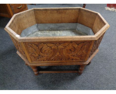 An octagonal carved oak and metal-lined planter on stand.