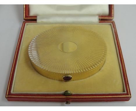 A cased 18 ct gold compact of oval reeded form with vacant cartouche to the top: cabochon ruby button to open