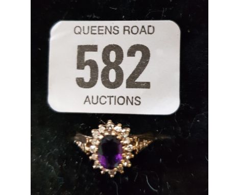 AN OVAL AMETHYST CLUSTER MOUNTED RING SET IN 9CT