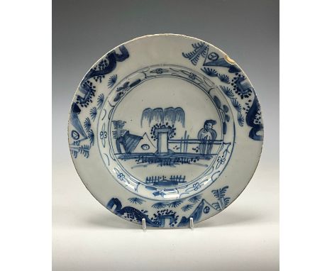 A 18th century English Delftware shallow dish, painted elder and garden on under glazed blue ground, 23cm high