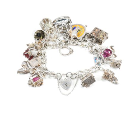 A hallmarked vintage silver charm bracelet. The bracelet strung with multiple silver and white metal charms to include, carri