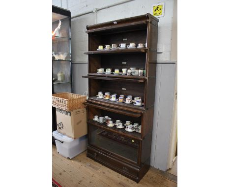 A Globe-Wernicke oak stacking bookcase, the five graduated shelves with glazed fall fronts, over a base drawer, 86.5 cm wide,