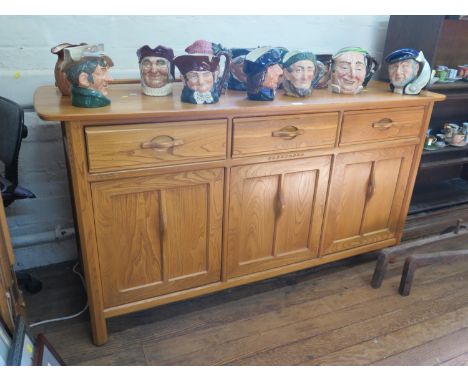 A light elm Ercol sideboard, with three frieze drawers over three panelled cupboard doors, on chamfered legs, 155 cm wide, 54