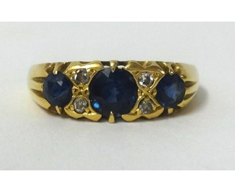 An 18ct three stone sapphire and diamond ring, finger size M.