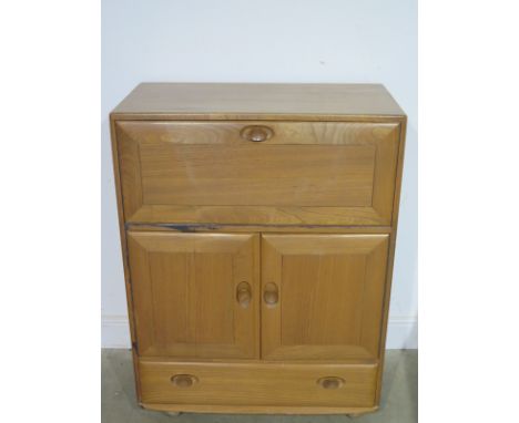 A mid 20th century Ercol light oak cabinet with fall down front, two door cupboard  and one drawer under, on later castors - 