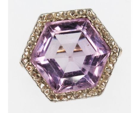 An early 20th century amethyst and diamond cluster ring, the central hexagonal cut stone measuring approx. 14mm x 13mm, depth