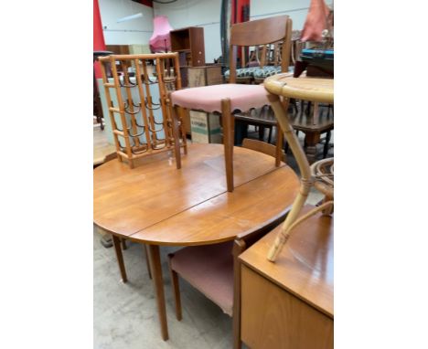 A mid 20th century teak dining suite, comprising a circular dining table with drop flaps, four chairs and a sideboard togethe