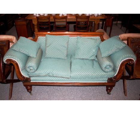 A Victorian mahogany scroll end sofa,&nbsp;having carved decoration and raised on turned baluster supports, upholstered in fl