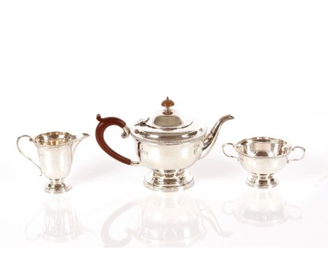 A silver three piece bachelors tea set,&nbsp;having beaded border decoration, the teapot with imitation wooden handle and lif