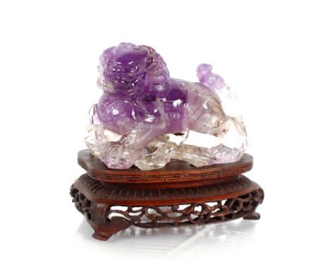 A late 19th / early 20th Century Chinese carved amethyst&nbsp;Dog of Fo,&nbsp;together with a pierced wooden stand 8cm long