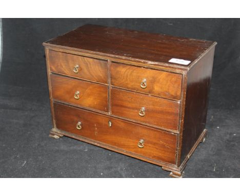 A 19th Century miniature mahogany chest with four short and one long drawer on ogee bracket feet and contents of various sewi