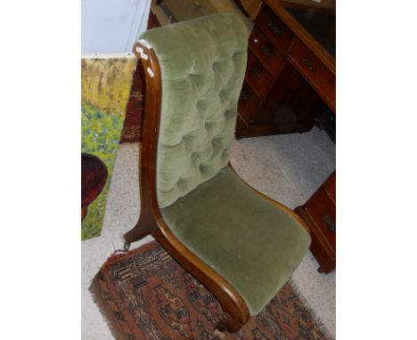A Victorian nursing chair, the green velvet upholstery with button back and mahogany show frame, raised on brass caps and cas