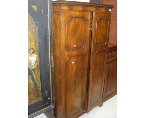 An Edwardian mahogany two door wardrobe, the moulded top with Greek key style design, above two panelled doors, raised on bra