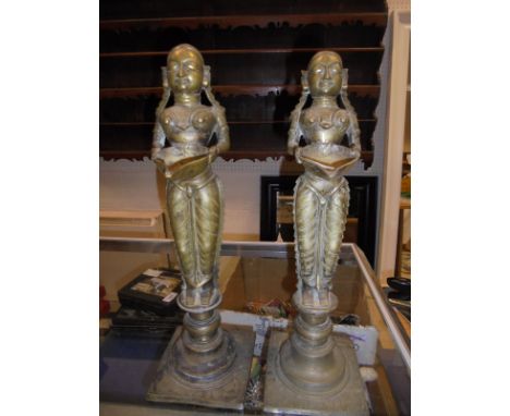 A pair of Indian brass oil lamp figures holding bowls, raised on turned circular plinths, together with an iron censer, the f