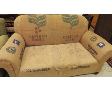 A hessian covered scroll arm sofa raised on bun feet
