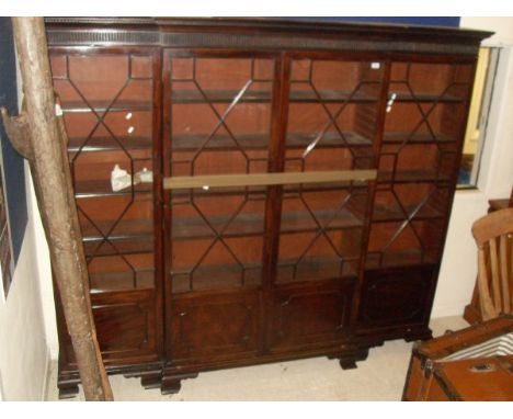 An early 20th Century mahogany break front bookcase in George III taste, the dental moulded cornice above a fluted frieze and