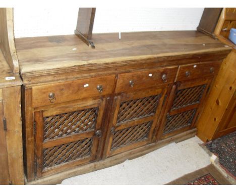 A Eastern hard wood dresser base with three drawers above three cupboard doors with latticed panels, the whole to bracket fee