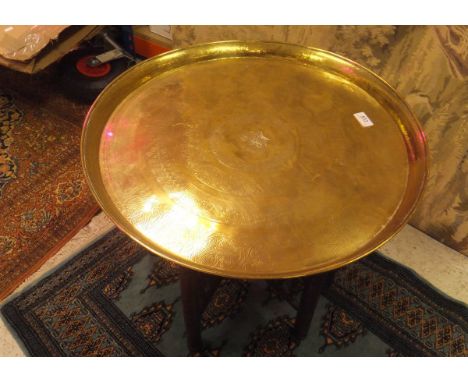 An Eastern coffee table with brass circular tray, raised on a hardwood folding base, together with a 20th Century needlework 