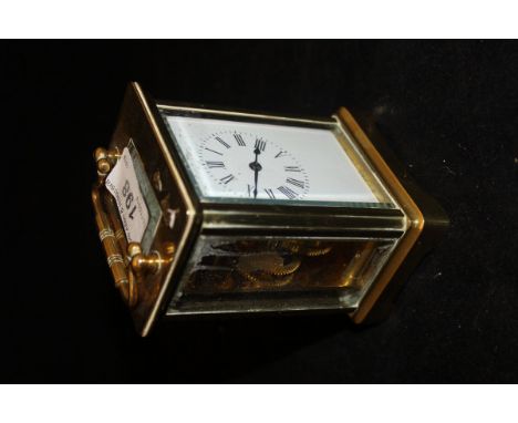 A circa 1900 French brass cased carriage clock with visible escapement, the enamelled dial with Roman numerals
