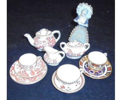 A Royal Crown Derby miniature porcelain tea set, together with two similar cups and saucers and a porcelain figure of a lady 