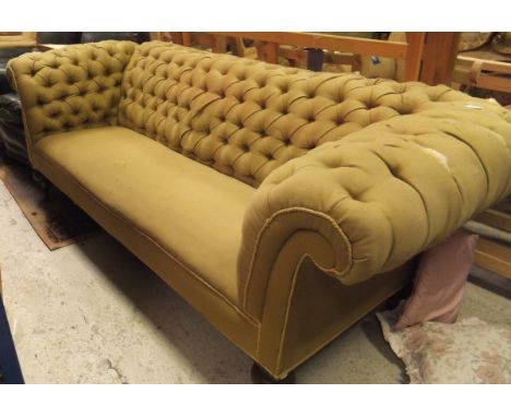 A three seater Chesterfield sofa in olive green button back upholstery, raised on mahogany turned legs to brass caps and cast
