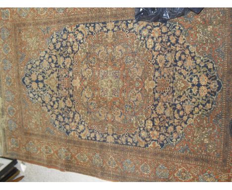 A Persian carpet, the central panel set with floral decorated stepped panels on a brown and blue ground within a stepped brow