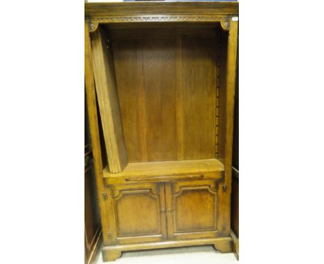 An oak bookcase with moulded cornice above two open adjustable shelves with brushing slide beneath and two panelled cupboard 