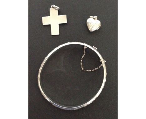 3 pieces of silver jewellery - an engraved bangle, a heart shaped locket and a cross.