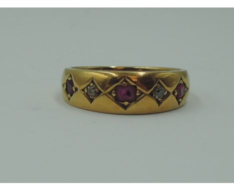 A lady's dress ring of band form having a trio of rubies interspersed by two diamonds in square settings on a yellow metal lo