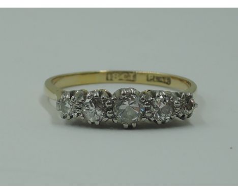 A lady's dress ring having five graduated diamonds in a claw set raised mount on a yellow metal loop stamped 18ct plat,  size