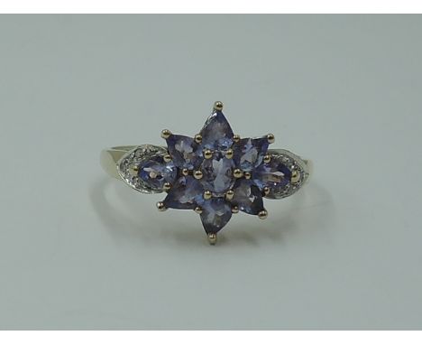 A lady's dress ring having a pale blue paste cluster with diamond chip set shoulders on a yellow metal loop stamped 375, size