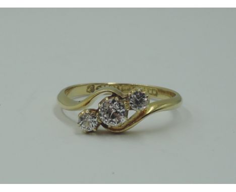 A lady's dress ring having a trio of clear stones, possibly white sapphires, in a claw set mount to crossover shoulders on an